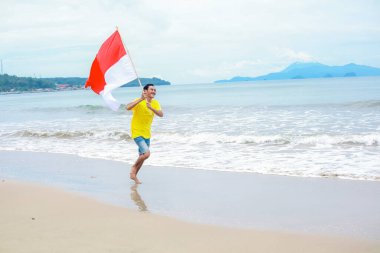Mutlu bir genç adam Endonezya bayrağıyla Bağımsızlık Günü 'nü kutluyor.