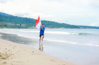 Kumsalda koşan bir adam, Endonezya Bağımsızlık Günü 'nü bayrağıyla kutluyor..