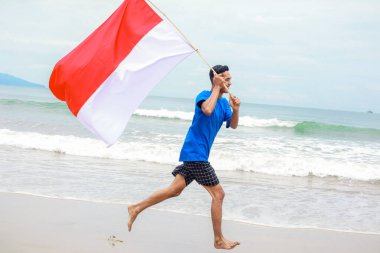 Bağımsızlık Günü kutlamalarında Endonezya bayrağıyla koşan hevesli bir adam.