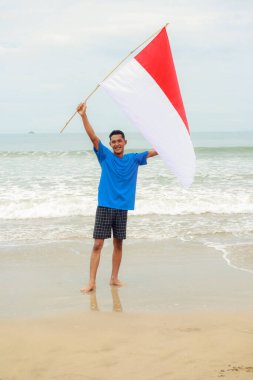 Genç bir adam neşeyle Endonezya bayrağını dalgalandırıyor.
