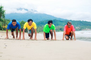 Bulutlu Gökyüzünün Altındaki Tropikal Plajda Yarışa Hazır Dört Arkadaş