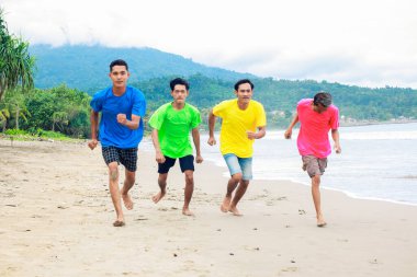 Dört Parlak Gömlekli Genç Tropikal Plajda Koşuyor