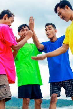 Canlı tişörtlü dört kişi dışarıda kutlama yapıyor.