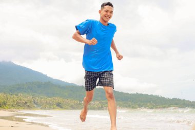 Okyanus manzaralı tropikal plajda koşan Mutlu İnsanlar
