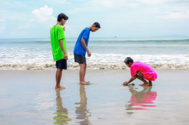 Sahilde oynayan üç genç yetişkin.