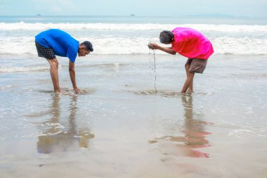 Güneşli bir sahilde sığ suda oynayan iki adam.