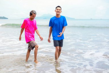 Güneşli bir plajda yürüyen iki adam