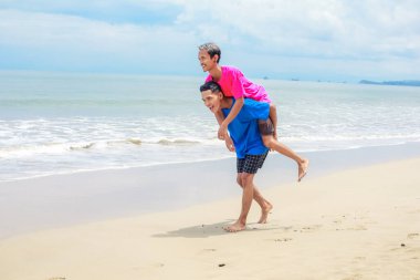 İki genç adam Sunny Beach 'te oynuyorlar, sırtına biniyorlar