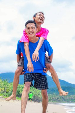 Kumsalda Neşeli Genç Erkekler Sırtına Biniyor