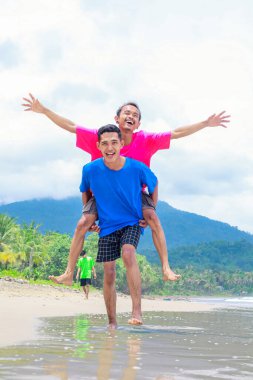 Tropik bir plajın tadını çıkaran iki mutlu adam.
