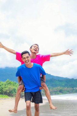 İki Adam Tropikal Sahilde Neşeli Bir Sırtta Yolculuk Yapıyor