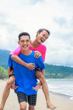 İki genç adam Sunny Beach 'te sırtımda gezintiyle eğleniyor.