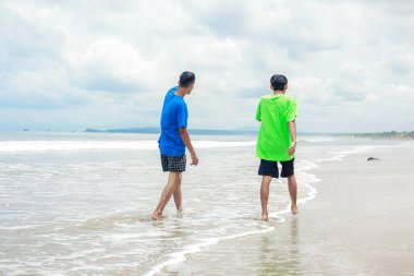 Bir yaz günü kumsalda gezinen iki adam