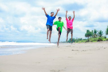 Üç adam sahilde eğleniyor.