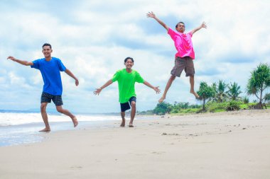 Güneşli Tropikal Sahilde Neşeli Üç Genç Adam Oynuyor