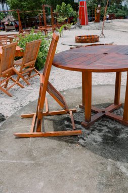 Sahilde, ahşap bir masa ve açık hava yemek ve rahatlama için sandalyeler.