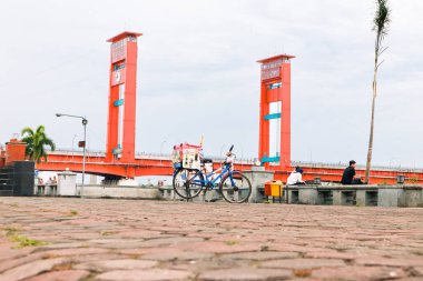Palembang, Endonezya 'daki Ampera Köprüsü' nü bir bisiklet ve rahat bir atmosferle yakalayan bir görüntü..