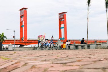 Palembang 'taki Ampera Köprüsü sokak yemeği bisikleti ve manzaranın tadını çıkaran insanlar.