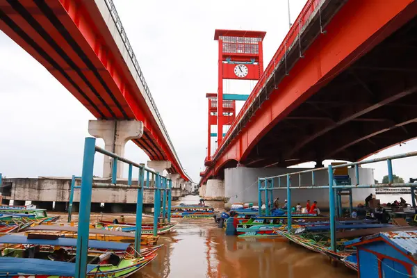 Palembang, Endonezya 'daki Ampera Köprüsü' nün canlı bir görüntüsü, Musi Nehri üzerinde, renkli yerel teknelerle.