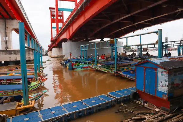 Nehir rıhtımında renkli teknelerle dolu Ampera Köprüsü 'nün altında canlı bir sahne..