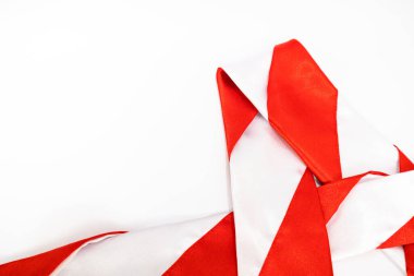 Parlak kırmızı ve beyaz şeritli kurdele beyaz bir yüzeye gelişigüzel yerleştirilmiş.