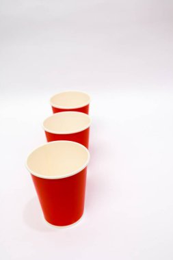 Temiz, beyaz bir zemine karşı düzgünce istiflenmiş kırmızı tek kullanımlık kağıt bardakların minimalist kompozisyonu