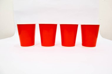 Dört parlak kırmızı bardağın, beyaz arka planda durduğu bir sahne, stüdyo çekimi.