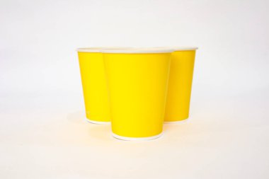 Beyaz arka planda izole edilmiş üç parlak sarı kağıt bardak tasarım ve reklam projeleri için mükemmel.