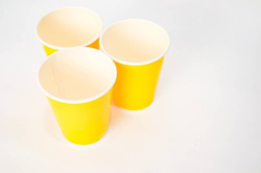 Beyaz arka planda üç sarı kağıt bardak, parti dekorasyonu için mükemmel.