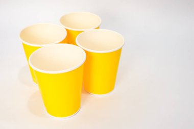 Beyaz zemin üzerinde dört sarı kağıt bardak, modeller ya da tek kullanımlık sofra takımları için mükemmel