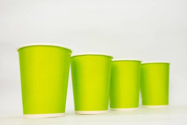 Beyaz arka planda boyutu gösteren dört sıra yeşil kağıt bardak..