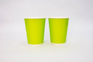 Beyaz arka planda iki parlak yeşil tek kullanımlık bardak. Tasarımlar ve ekolojik ürünler için uygun.