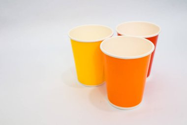 Beyaz arka planda üç renkli kağıt bardaktan oluşan minimalist bir stüdyo..