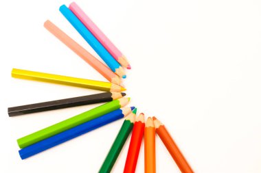 Yaratıcılığı resmetmek için ideal beyaz bir yüzeye yerleştirilmiş renkli kalem koleksiyonu.