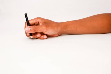 Koyu tenli bir el beyaz arkaplana yazmaya ya da çizmeye hazır bir kalem tutuyor.