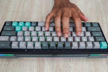 Ahşap bir masanın üzerinde renkli bir klavyeye yazı yazan elleri kapat