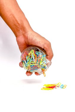 Elinde renkli ataçlarla dolu bir kavanoz var. Bazıları beyaz bir yüzeye dökülüyor.