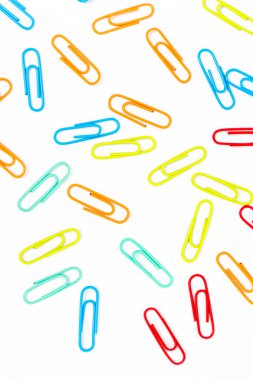 Beyaz arka planda renkli ataçlar, basit ve temiz bir ofis malzemesi düzenlemesi.