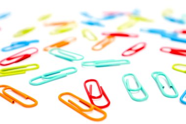 Beyaz arkaplana saçılmış renkli ataçların yakın çekimi