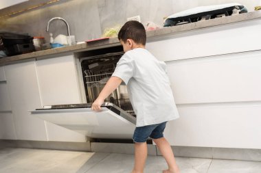 Çocuk modern mutfakta bulaşık yıkıyor..