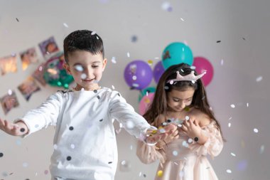 Paper multicolored confetti falling on heads of smiling happy children on birthday party. clipart