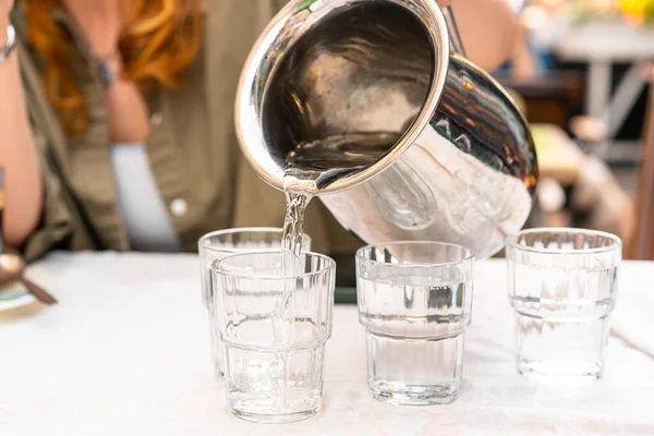 stock image Waiter pouring water into glasses, restaurants service.