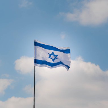 Israeli flag waving in the wind against the blue sky and white clouds on sunny day. Independence day Israel - Yom Haatzmaut . clipart
