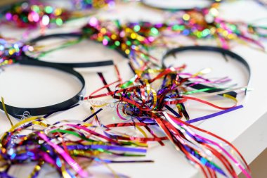 Doğum günü ya da parti hazırlıkları için neşeli Tinsel saç bantları. Renkli Saç bantları Partiye Hazır. Şenlikli Tinsel Saç bantları Bir Masada Ayarlandı, Doğum Günlerini ve Özel Günleri Kutlamak İçin Mükemmel.