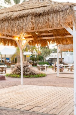 Akşam ışıkları ve şehir arkaplanlı saman plaj şemsiyesi. Veranda şemsiyesi..