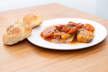 Lezzetli Yahudi Şabat Lezzeti: Fas Balık Chraime 'si, canlı domates sosu, biber ve havuç, beyaz tabakta servis edilir. Challah Buns 'ın yanında. Geleneksel, şenlikli, lezzetli.