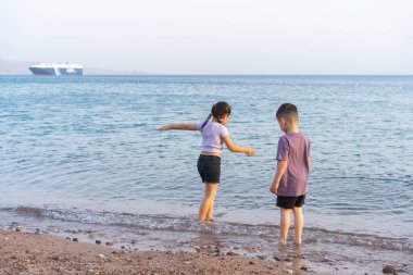 Kumsalda oynayan şirin küçük çocuklar. Yaz günü deniz kenarında yürüyen iki çocuk, yaz tatilinin tadını çıkarıyorlar..