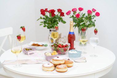 Hanuka 'nın sıcaklığı. Şampanyalı güzel ahşap masa, bir vazo Luscious Strawberries, ve bir dizi salata, geleneksel Sufganiyot-Yumuşak Donutlar Pudra Şekeri ve Lezzetli Reçelli.