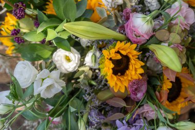 Ayçiçekleri, güller ve diğer çiçeklerin yer aldığı canlı çiçeklerin yakın çekim görüntüsü. Renkli karışım her birinin güzelliğini ve detaylarını vurguluyor..