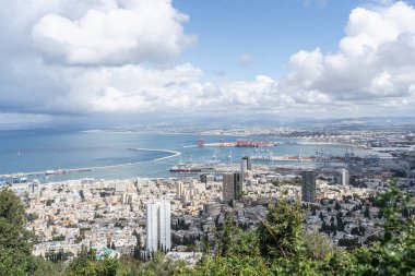 Kalabalık liman kenti Hayfa, İsrail, şehrin ve Akdeniz kıyı şeridinin geniş görüş açısına sahip yüksek bir noktadan görüldü. Endüstriyel vinç ve binalar, huzurlu deniz ve gökyüzü ile tezat oluşturuyor.